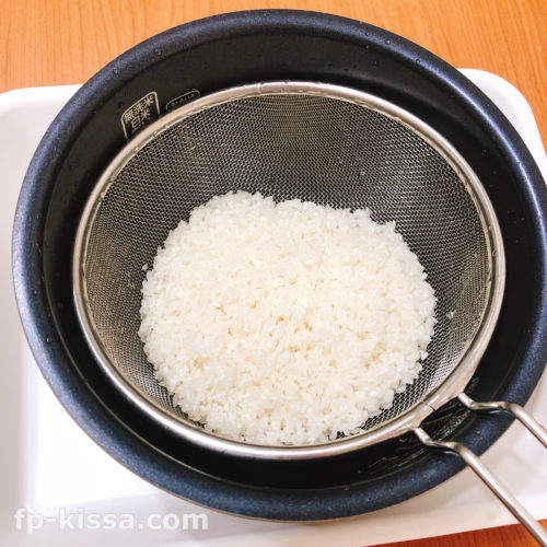 洗った米をざるにあげる